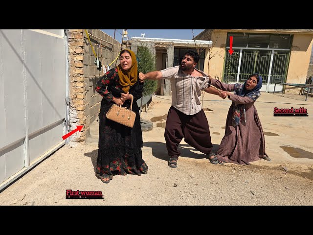 The husband stops the first wife from leaving the house: the second wife gets angry.