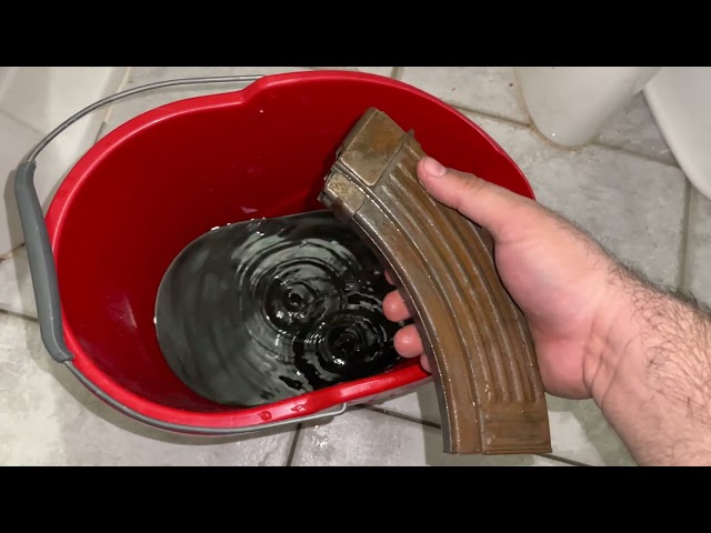 Serbian AK 47 magazines with rust submerged in Coca Cola overnight preparing to spray paint them