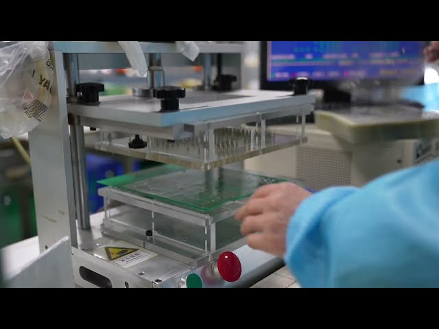 The machine is covering the metal dome array with a layer of PET film