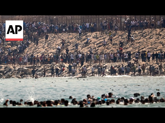Thousands of migrants swim around the border from Morocco into Ceuta, Spain